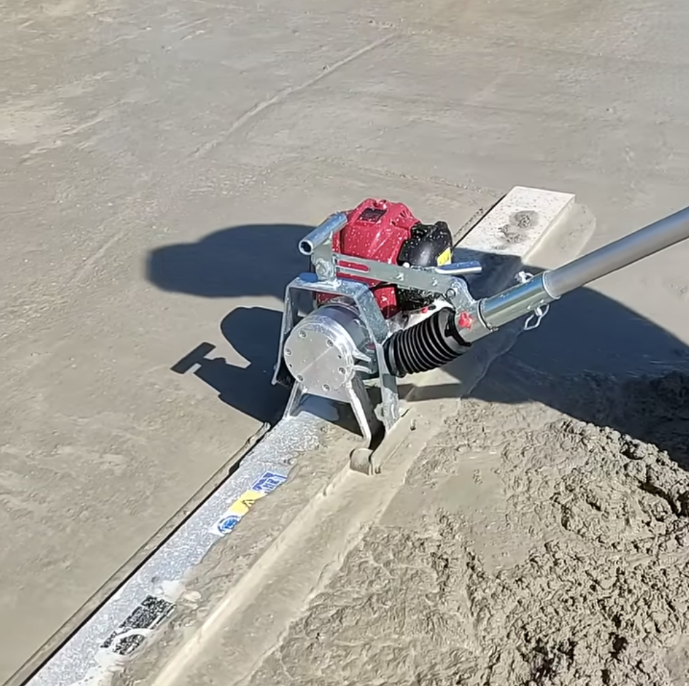 Listwa wibracyjna do betonu w trakcie pracy – urządzenie zagęszcza i wyrównuje świeżo wylany beton na placu budowy.